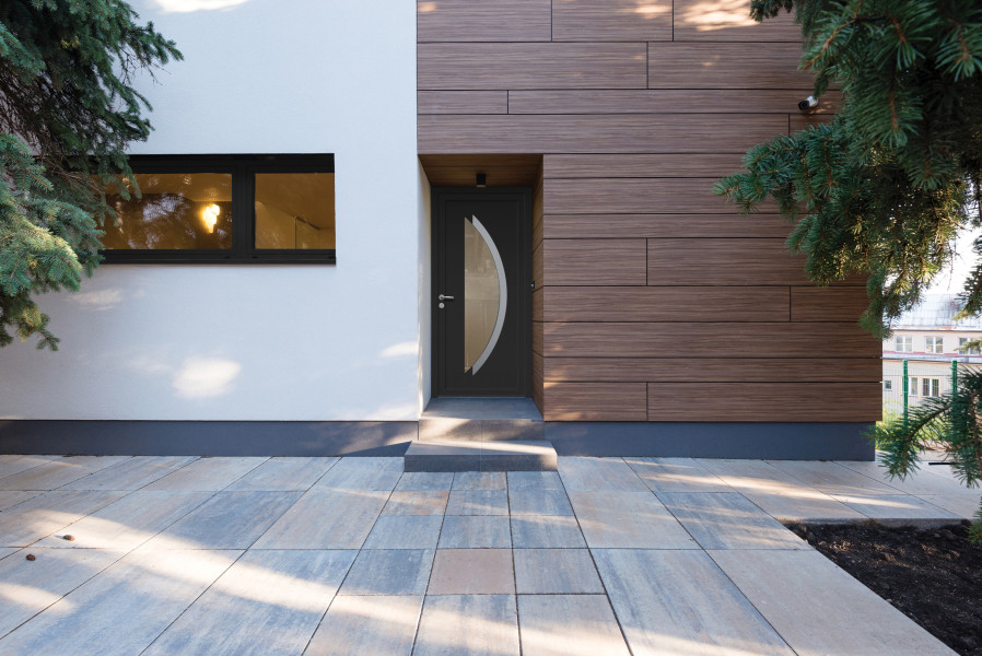 Porte d'entrée PVC Gange - Visuel d'ambiance Maison moderne vue de l'extérieur avec porte d'entrée grise et décor arc vitré et inox